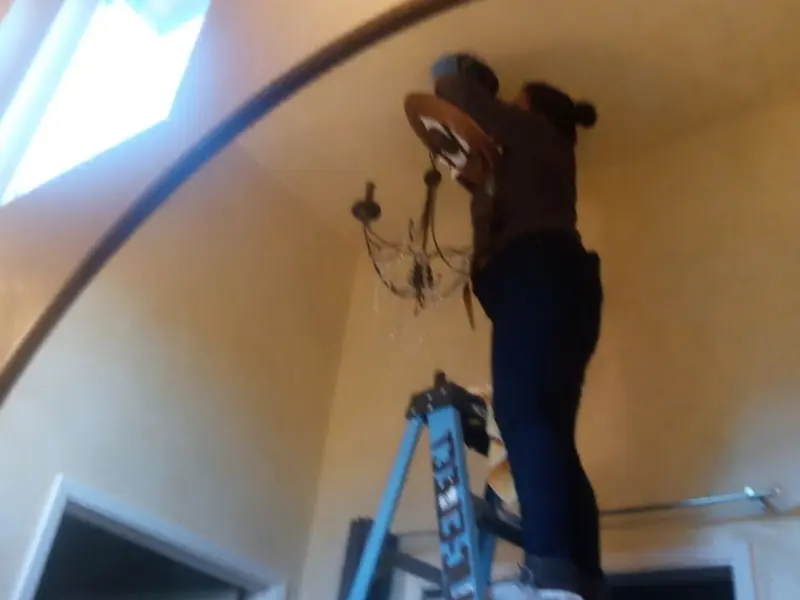 Electrician installing a chandelier in a Valley residence